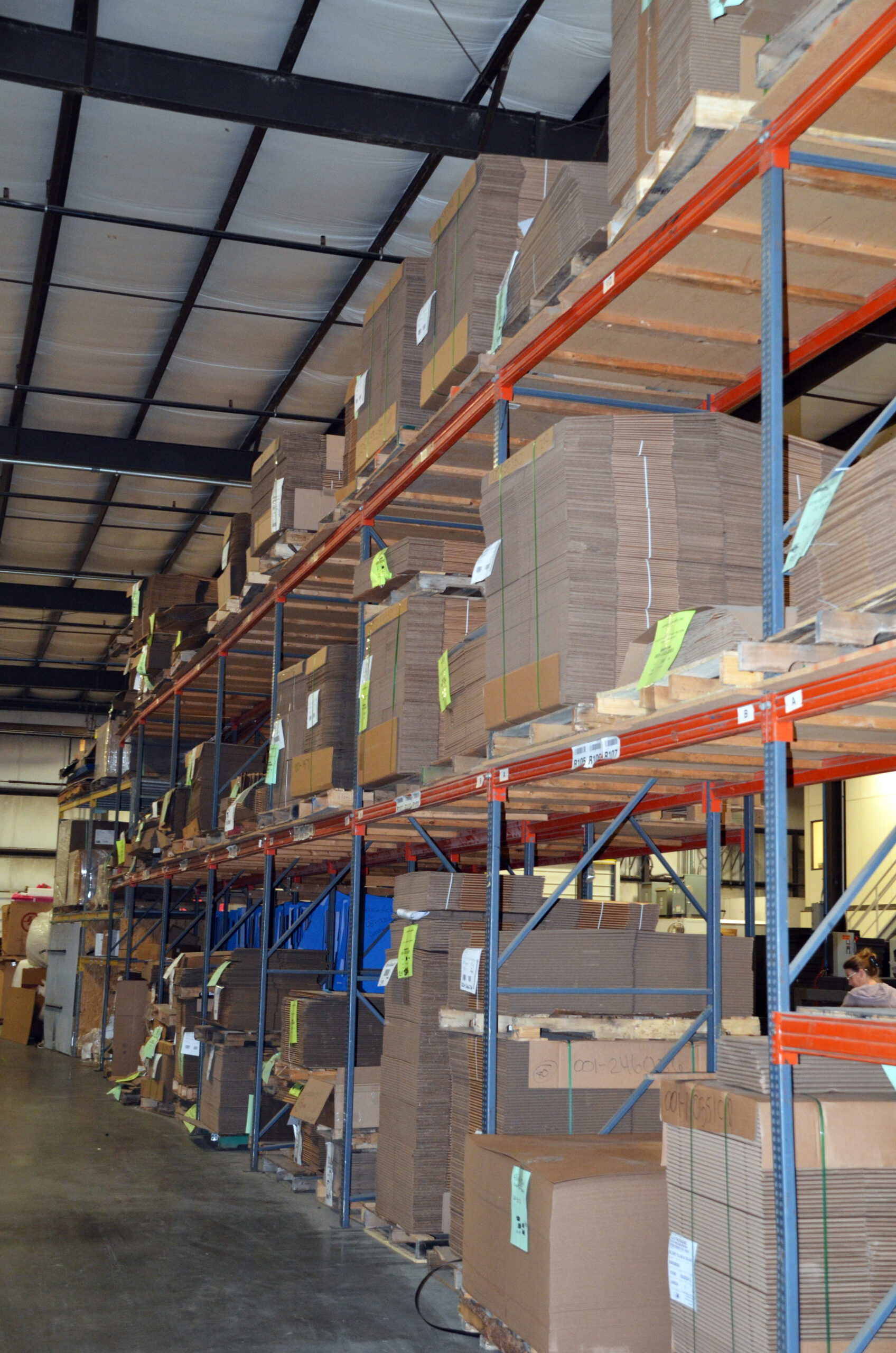 Warehouse shelving with stacked corrugated cardboard inventory.