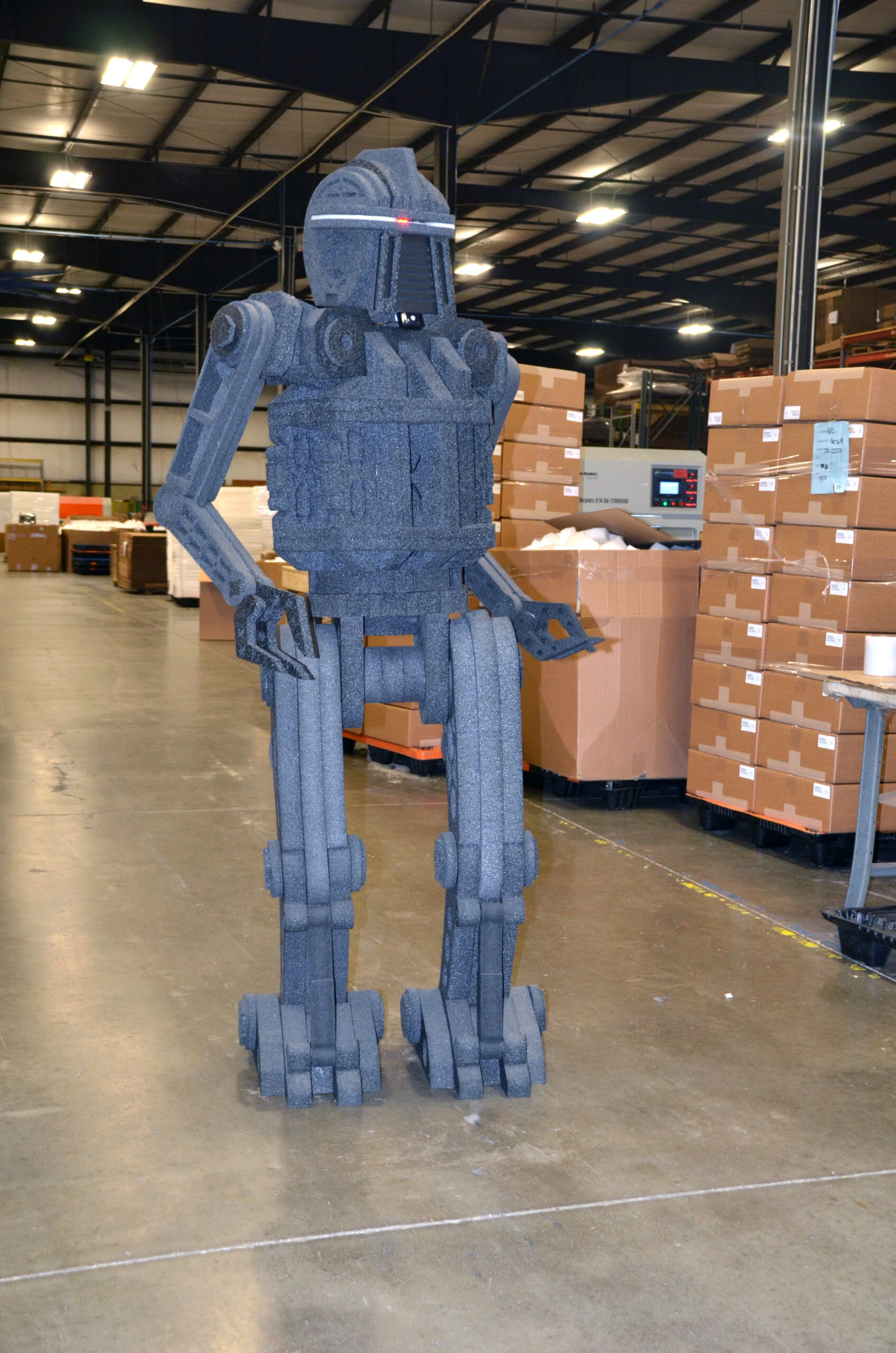 Foam robot figure displayed in a warehouse environment.